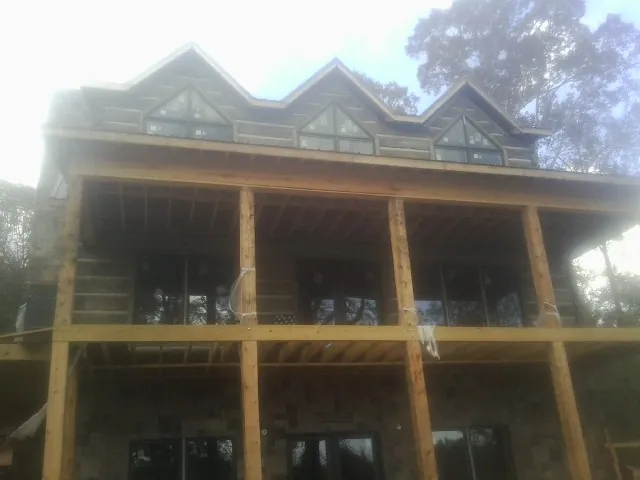 Dormers and porch framing on a large log home under construction — Roof Coating work by our crew in Crestwood