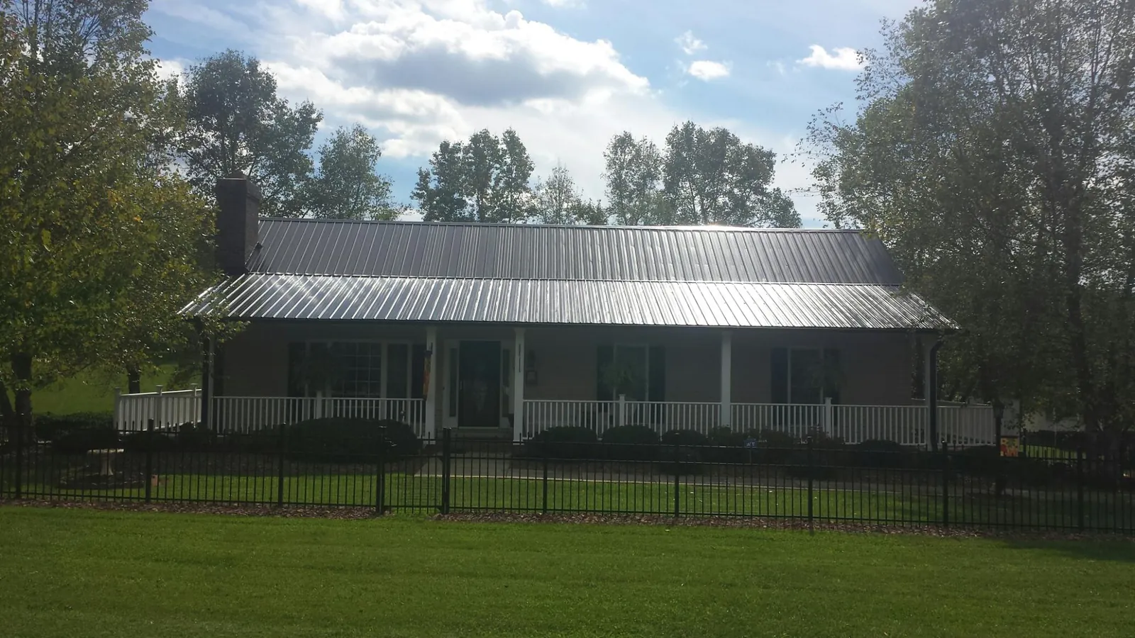 Gray metal roof on a brick ranch with a full width front porch — Gutter Guard Installation work by our crew in Crestwood