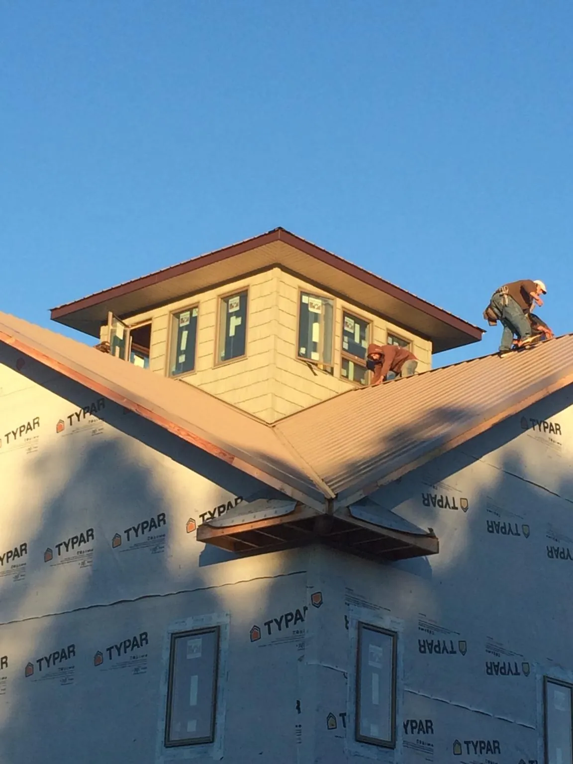 Roofers working around a rooftop cupola on a new metal roof at sunset — Roof Waterproofing in Crestwood by Roofing Brothers